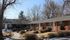 Quaint brick apartment complex surrounded by trees and a well-kept garden pathway.