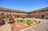 Charming apartment complex with well-maintained gardens and blooming flowers under a clear blue sky.
