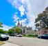 A picturesque street view featuring a grand historic building with towering spires and a clear blue sky.