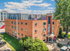 Charming brick apartment building in a vibrant urban neighborhood with modern architecture and lush greenery.
