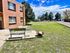 Charming apartment building with outdoor seating on a sunny day, featuring a lush green lawn.
