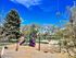 Bright playground featuring purple slides, climbing structures, and swings surrounded by lush greenery.