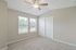 Bright and airy bedroom with plush carpeting, large windows offering scenic views, and a modern ceiling fan for comfort.