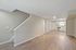 Contemporary open living space with elegant hardwood floors, modern kitchen, and stylish staircase.