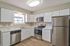 Modern kitchen with sleek white cabinetry, stainless steel appliances, and elegant light fixtures.