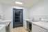 Modern laundry room with sleek white appliances, stainless steel counters, and elegant blue door, offering functionality and style.
