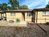 Charming brick exterior of a cozy home with a welcoming open door, surrounded by a low-maintenance rock garden and lush greenery.