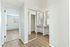 Elegant apartment hallway with mirrored closet doors, sleek wooden floors, and bright natural light.
