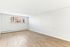 Bright and spacious room with elegant hardwood flooring and large window, perfect for a cozy living area.