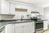 Modern kitchen with sleek white cabinetry, stainless steel appliances, and a stylish black countertop.