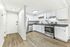 Bright and modern kitchen with sleek white cabinets, stainless steel appliances, and elegant wood flooring.