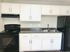 Modern kitchen with sleek white cabinets, black appliances, and a spacious countertop, perfect for culinary creativity.