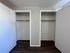 Spacious dual closets offering ample storage space with sleek wooden flooring and minimalistic design.
