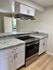 Modern kitchen with sleek granite countertops, contemporary white cabinetry, and stainless steel appliances.