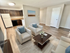 Chic open-concept living room with modern furniture, bright kitchen, and elegant wood flooring.