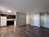 Modern open-plan kitchen and living area with elegant dark wood cabinetry and sleek flooring, offering a spacious and inviting environment.