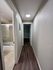 Elegant apartment hallway with modern wood flooring and a brightly lit bathroom entrance.