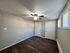 Bright and inviting room with elegant wood flooring, featuring a ceiling fan and ample natural light from modern windows.