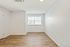 Bright and inviting room with elegant wooden flooring and a large window offering abundant natural light.