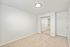 Bright and spacious bedroom with plush carpet, sleek mirrored closet doors, and modern overhead lighting, perfect for comfortable living.
