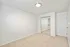 Bright, modern bedroom with plush carpet, mirrored closet doors, and sleek lighting fixture.