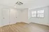 Bright, modern room with sleek wooden flooring, ample natural light from large windows, and minimalist design for versatile living.
