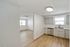 Bright and modern kitchen with stainless steel appliances, elegant cabinetry, and rich hardwood floors, seamlessly opening into a sunlit living area.