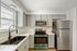 Modern kitchen with sleek gray cabinets, marble countertops, stainless steel appliances, and a large window providing abundant natural light.