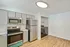 Modern kitchen with stainless steel appliances, wood flooring, and convenient in-unit laundry space.