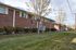 Welcoming brick apartment complex with lush green landscaping, mature trees, and a serene neighborhood setting.