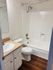 Bright and modern bathroom featuring a sleek bathtub-shower combo, elegant vanity with ample storage, and stylish wood flooring.