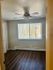 Inviting bedroom with natural light, elegant wood flooring, and modern ceiling fan.