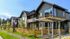 Charming modern apartments with inviting exteriors, featuring wooden fencing and a lush green landscape under a clear blue sky.