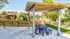 Charming outdoor space with a modern pergola, picnic tables, and vibrant greenery, perfect for relaxation in a friendly community setting.