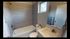 Modern bathroom featuring sleek grey tiles, a cozy bathtub, and a stylish vanity with a large mirror.