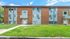 Charming brick apartment building with modern accents, surrounded by lush green lawn under a clear blue sky.