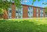 Charming brick apartment building surrounded by lush greenery and vibrant trees, offering peaceful living in a serene environment.