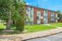Charming apartment building with brick facade, well-maintained lawns, and mature trees, perfect for serene living.