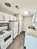 Modern kitchen with sleek granite countertops, white cabinetry, and a full-size refrigerator, offering a bright and inviting space.