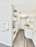Bright and modern galley kitchen with sleek white cabinetry, granite countertops, and elegant wood flooring.