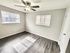 Bright and airy room with elegant dark wood flooring and modern ceiling fan, perfect for a cozy bedroom setup.