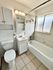 Modern bathroom featuring sleek white fixtures, a chic mirrored cabinet, and elegant tile flooring.