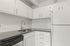 Modern kitchen with sleek white cabinets, elegant herringbone backsplash, and polished countertop, offering a stylish cooking space.