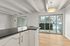 Modern apartment interior showcasing a sleek kitchen countertop leading to a bright dining area with large sliding glass doors opening to a cozy balcony view.