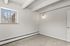 Bright and cozy room with large window, plush carpet, and modern sconce light, perfect for creating a personal retreat.