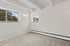 Bright, minimalist room with plush carpet, two large windows, and stylish wall light, offering a cozy and inviting atmosphere.