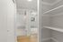 Bright and inviting hallway with open shelving and view into a cozy living space featuring natural wood flooring.