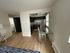 Modern apartment interior with sleek kitchen, glass-top dining area, and elegant wooden flooring, perfect for urban living.