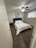 Inviting bedroom with plush carpet, featuring a comfortable bed, stylish artwork, and a modern ceiling fan.