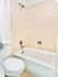 Bright and clean bathroom with modern fixtures, featuring a pristine shower-tub combo and elegant tile work.